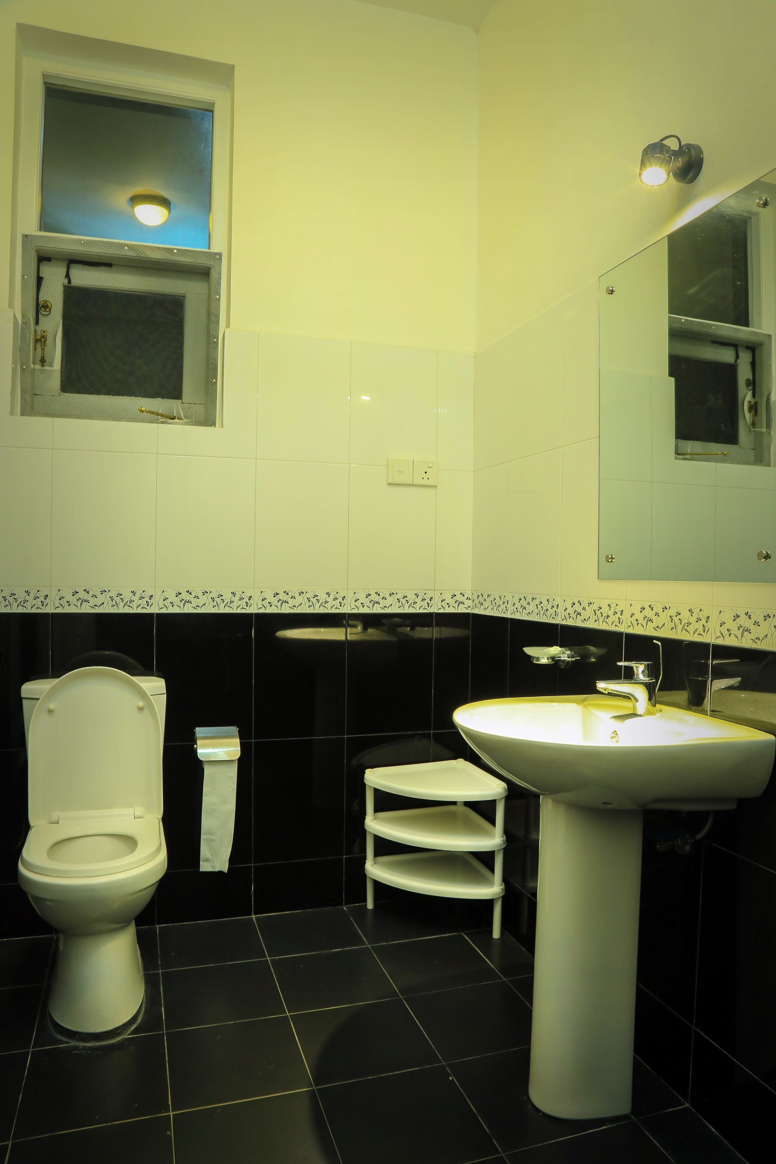 A bathroom with a toilet, sink, and a small window above the toilet.