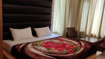 A bedroom with a wooden bed frame, a headboard, and a floral bedspread.