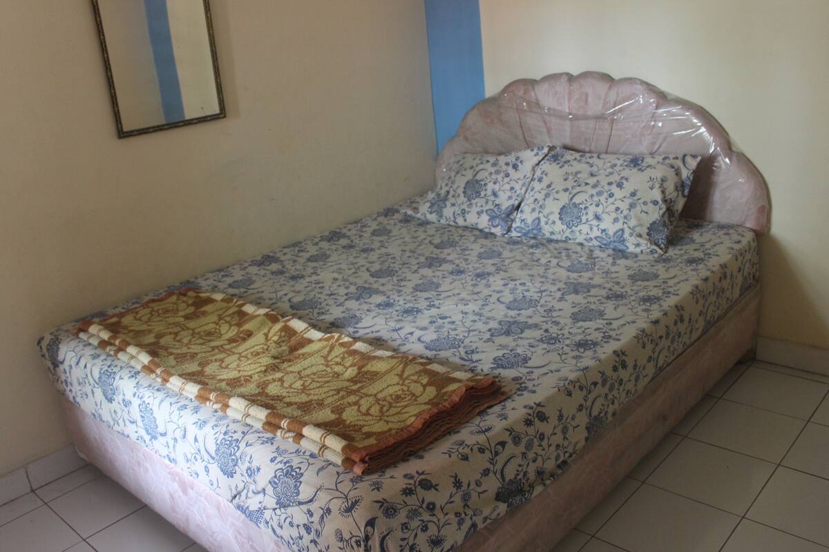 Una cama con un edredón floral y una manta decorativa.