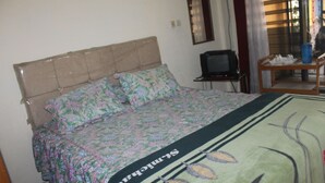 A bedroom with a bed, a television, and a small table with a blue vase. - Hotel Sakato (Bukittinggi)