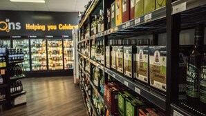 A liquor store with shelves stocked with various bottles and boxes of wine and spirits.