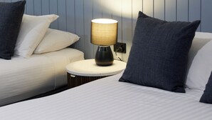 A hotel room with a bed, a bedside table with a lamp, and a wall with framed pictures.