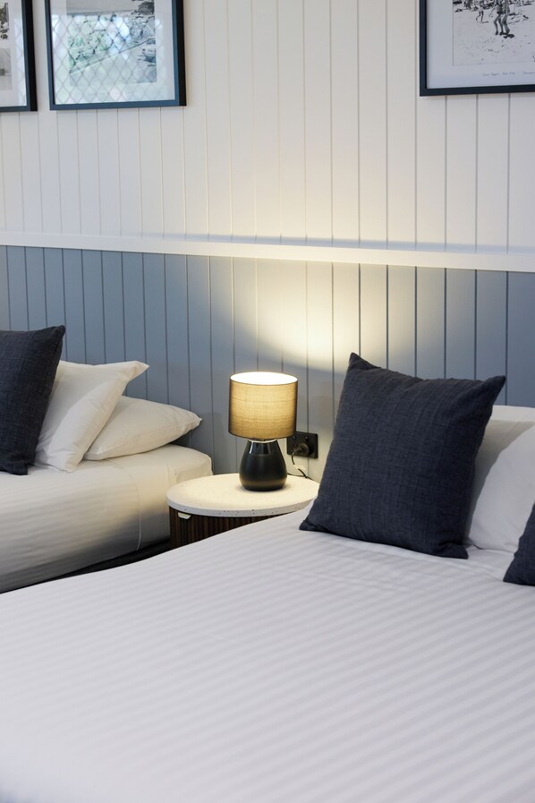 A hotel room with a bed, a bedside table with a lamp, and a wall with framed pictures.