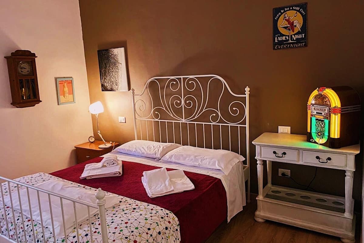 Un dormitorio con cama, mesita de noche, lámpara, jukebox y cuna.