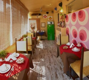 A restaurant with wooden walls, a green refrigerator, and tables set with white tableware.