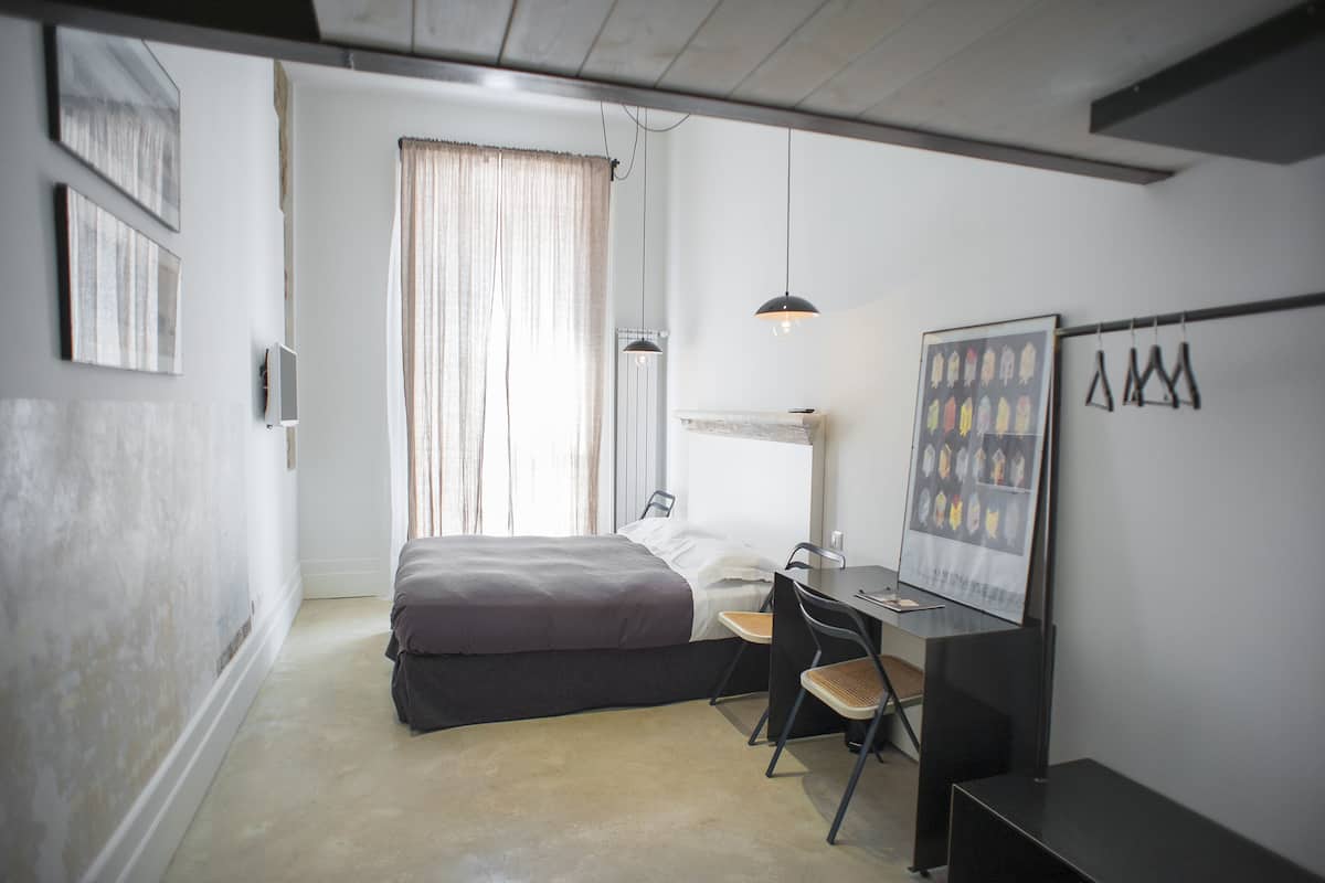 Un dormitorio con cama, escritorio, silla y una obra de arte en la pared.