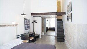 Un dormitorio con cama, escritorio, silla y una escalera que lleva a un nivel superior.