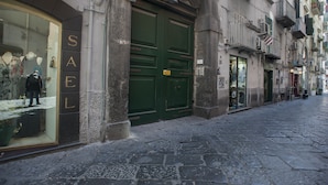 Una calle con una tienda llamada "SAEL", con una puerta verde grande y un maniquí en la ventana.
