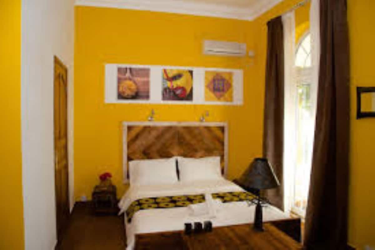 A room with a bed, a nightstand, a lamp, and artwork on the wall.