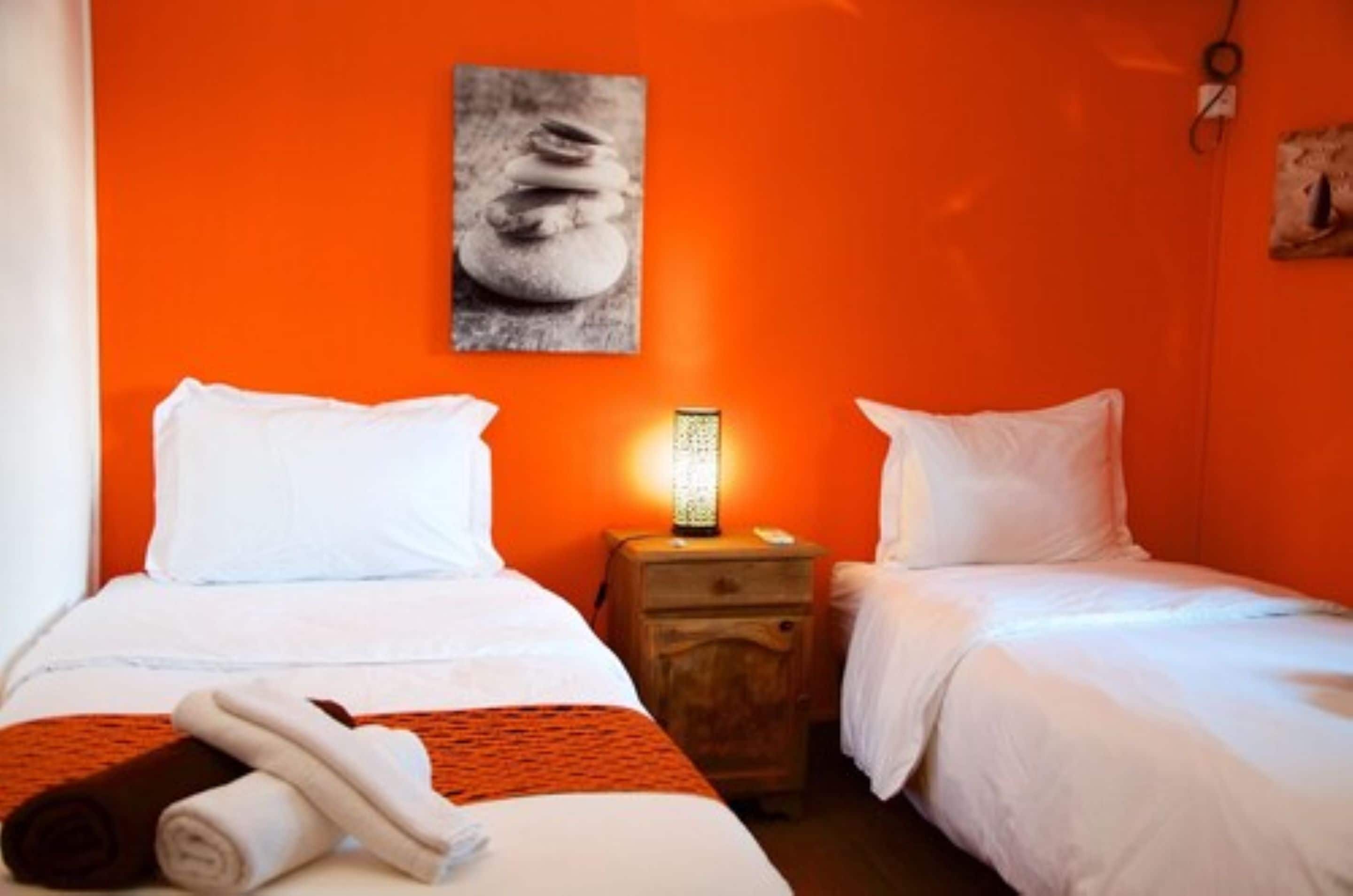 A hotel room with two beds, a nightstand with a lamp, and a painting on the wall.