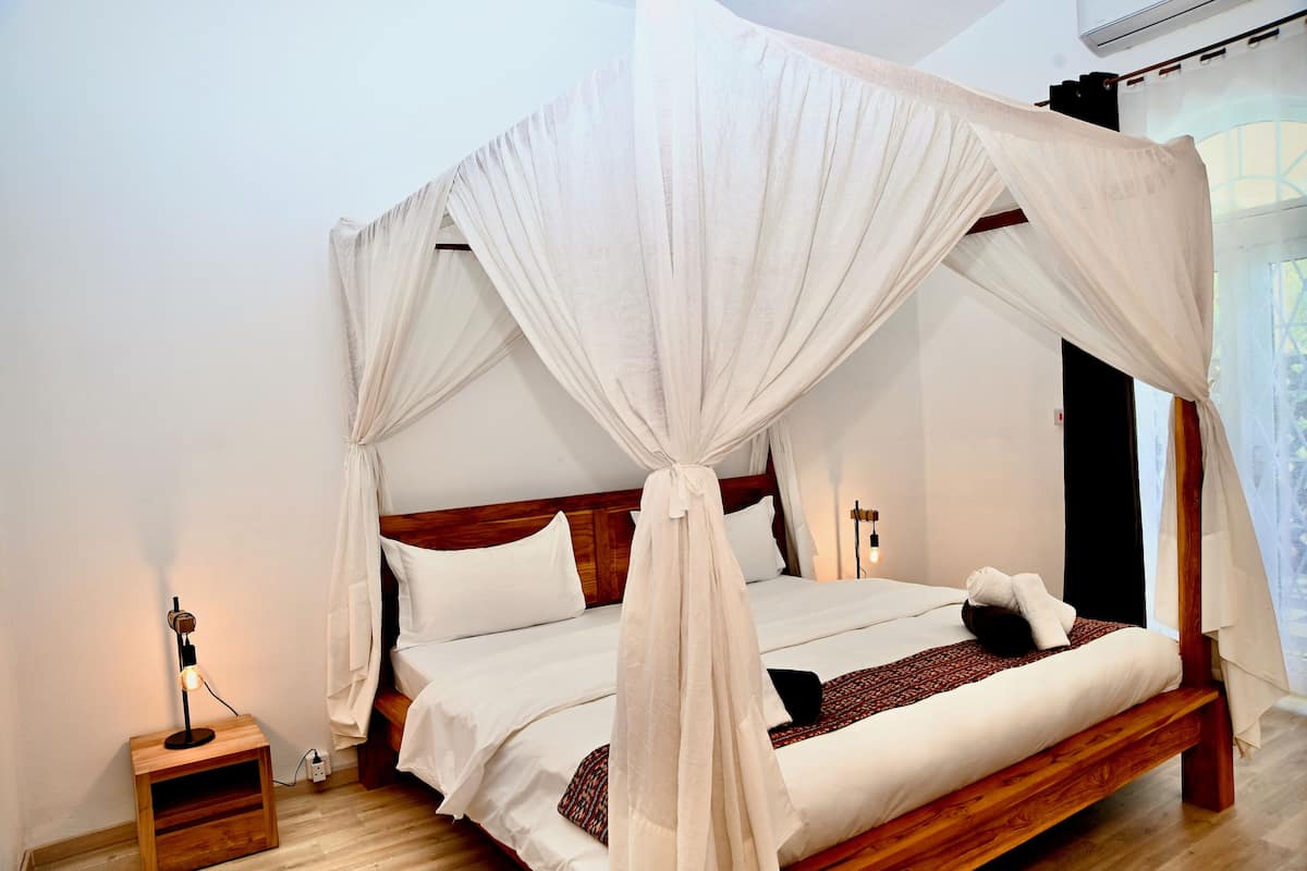 A bed with a canopy, a bedside table with a lamp, and a wall-mounted air conditioner.