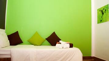 A hotel room with a green wall, a bed with white bedding, and two pillows.