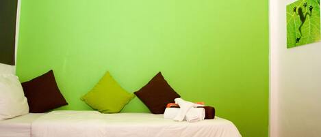 A hotel room with a green wall, a bed with white bedding, and two pillows.
