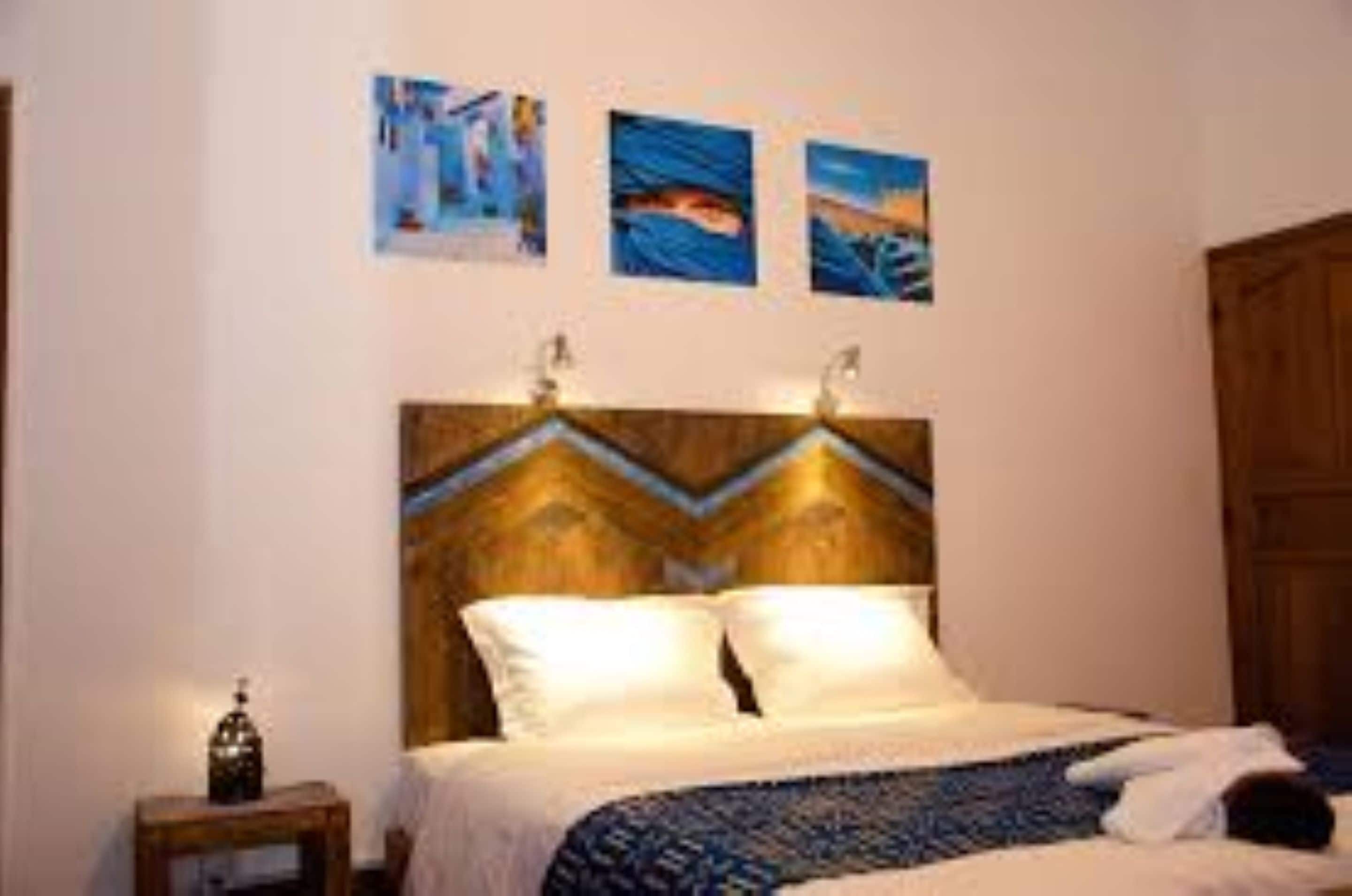 A bedroom with a bed, a nightstand, and wall art.