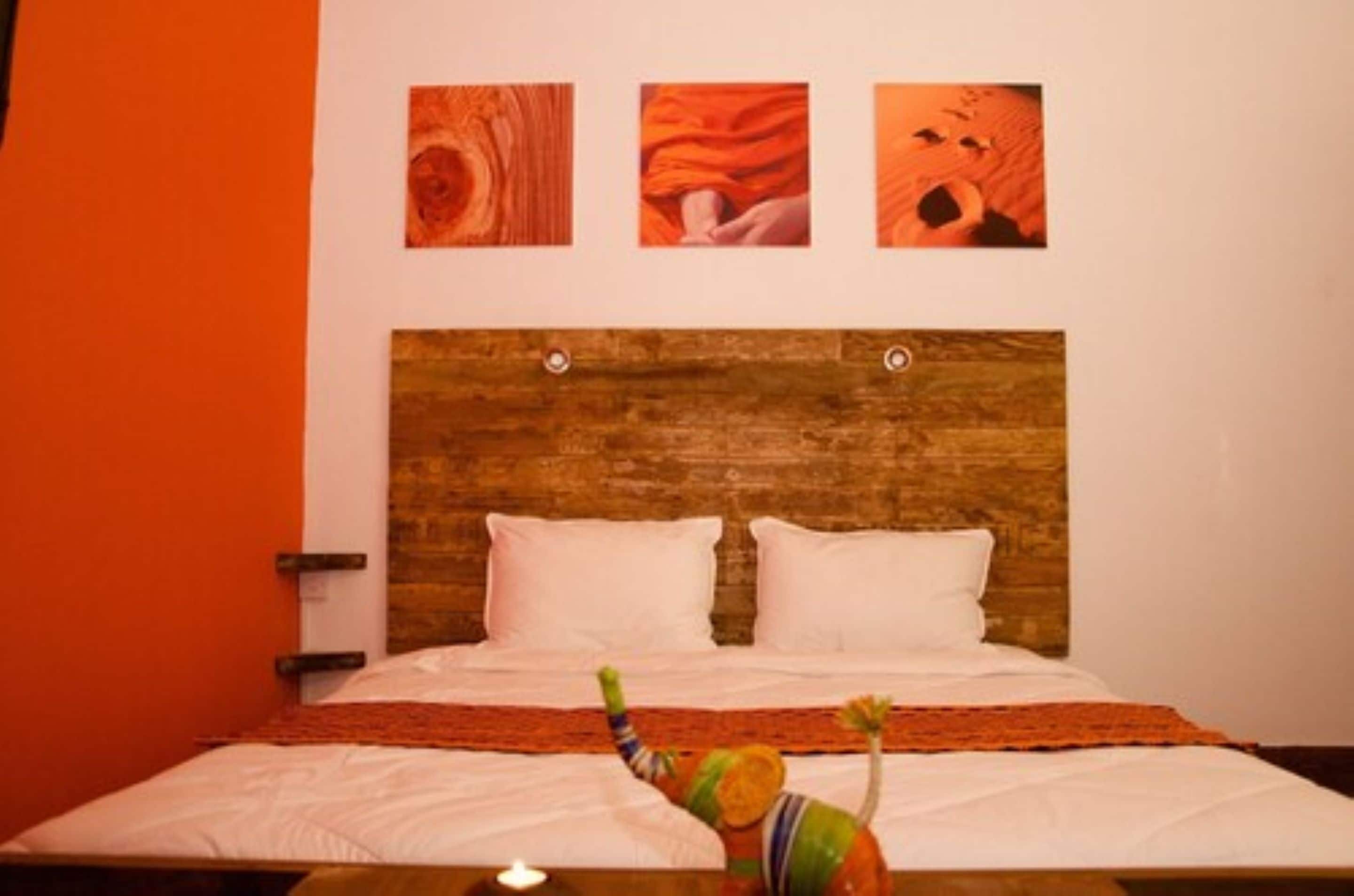 A bed with a wooden headboard, white pillows, and a colorful blanket.