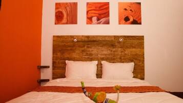 A bed with a wooden headboard, white pillows, and a colorful blanket.