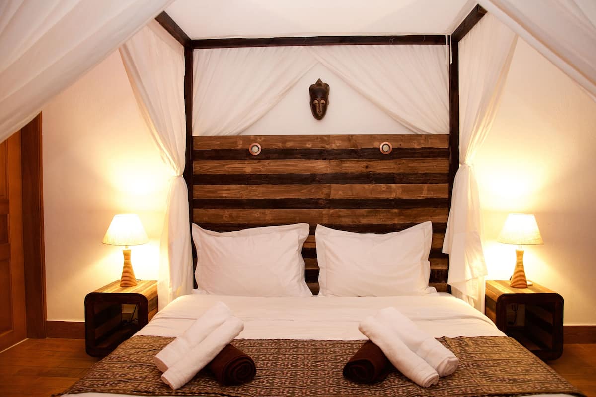 A bed with white linens, two bedside lamps, and a wooden headboard.