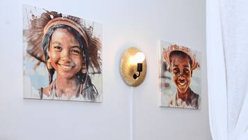 Two wall-mounted paintings with a wall-mounted light fixture between them.