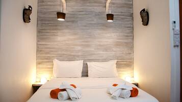 Quarto de hotel com uma cama grande, duas luminárias laterais e um telefone fixado na parede.