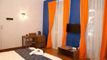 Una habitación de hotel con cama, escritorio, silla, televisión y cortinas.