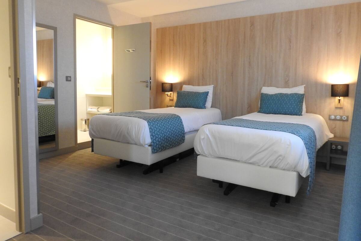 Habitación de hotel con dos camas, una pared de madera y lámparas de noche.