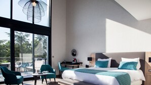 A modern hotel room with a large bed, a desk, and chairs. - LOGIS HOTEL RELAIS SAINT JACQUES (Coings)