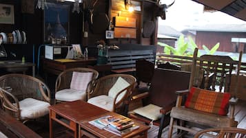 A rustic outdoor seating area with wicker furniture and a wooden table, surrounded by various items and decorations.