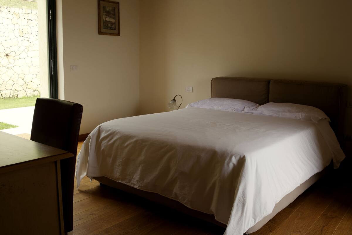 A bedroom with a bed, a chair, and a desk.