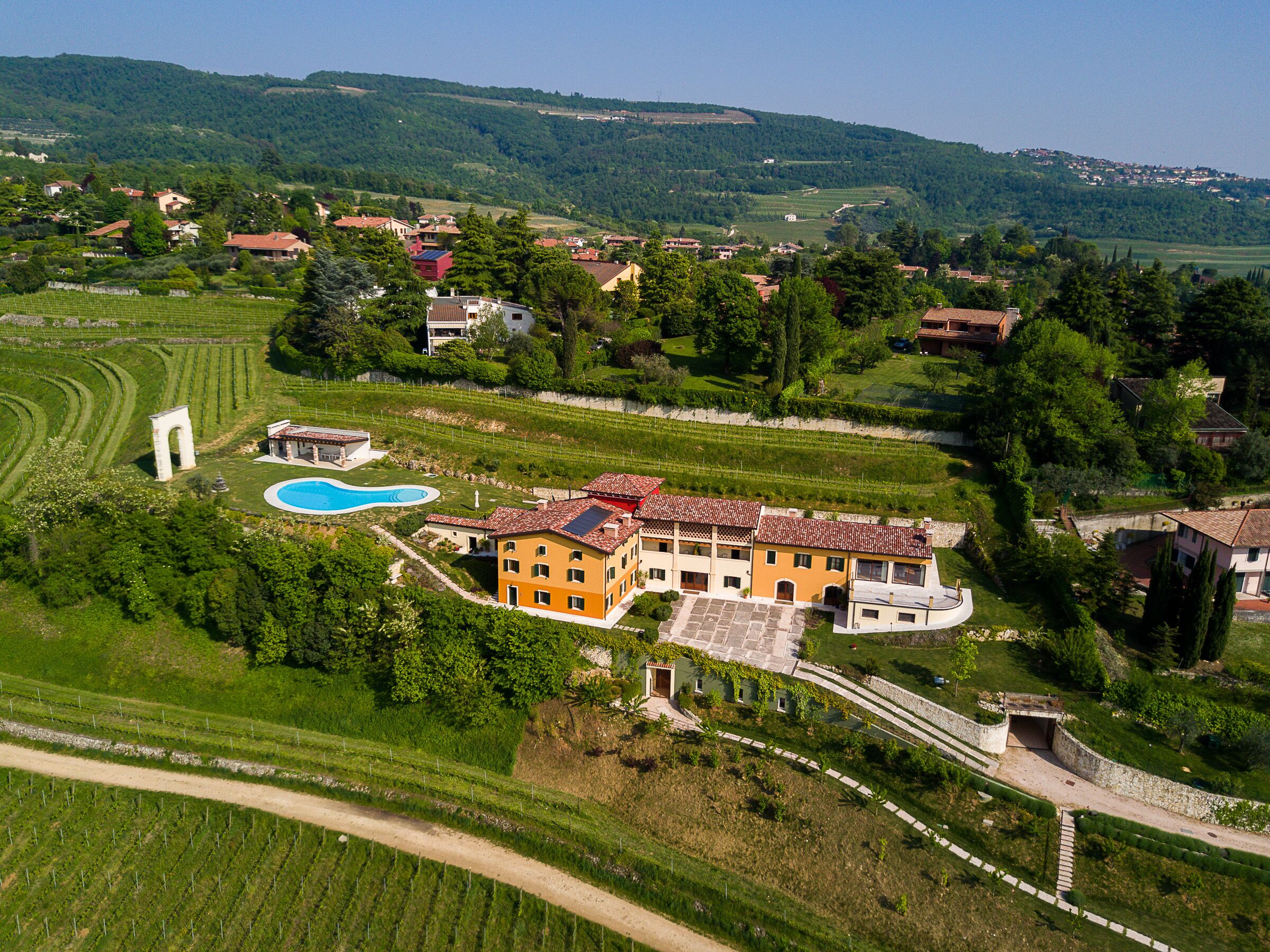 Une vaste villa dotée d’une piscine, entourée d’une végétation luxuriante et de vignobles.