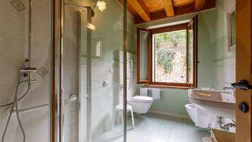 A bathroom with a glass-enclosed shower, a toilet, and a sink.
