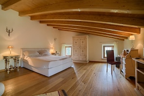 A bedroom with a wooden ceiling, a bed, a desk, and a cabinet.