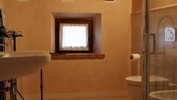Une salle de bain avec un plafond en bois, une fenêtre avec un rideau, des toilettes et une cabine de douche en verre.