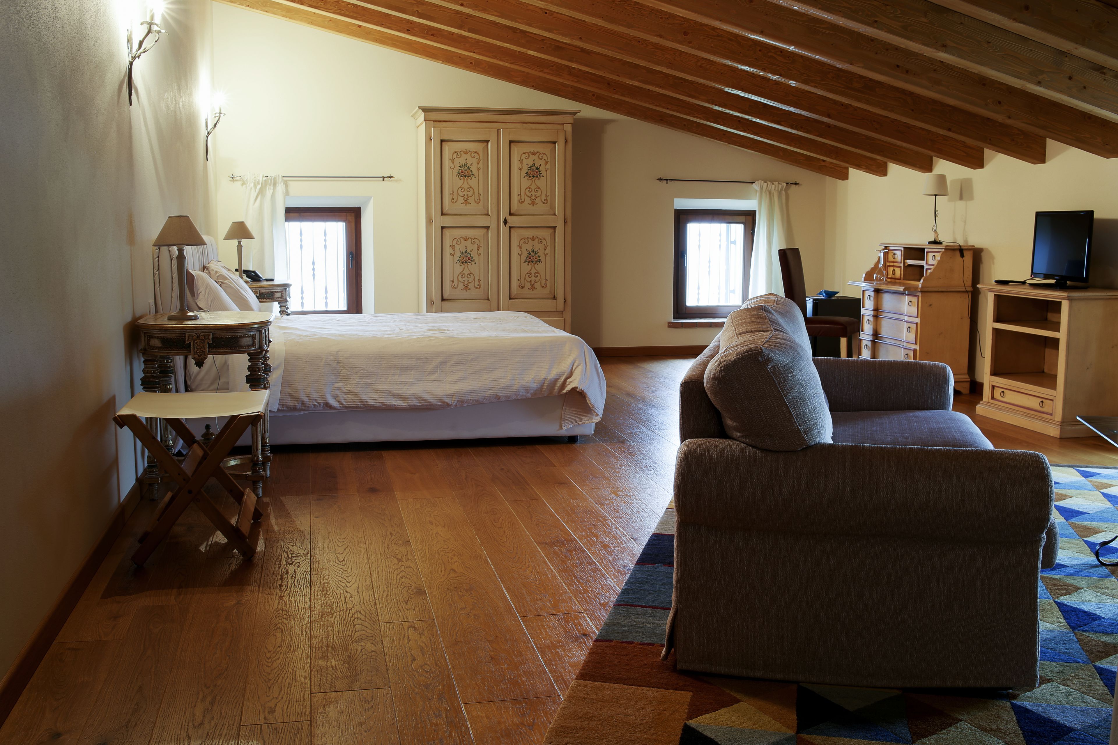 Una camera da letto con un letto, una sedia, una cassettiera, una televisione e una finestra.