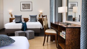 Habitación de hotel con dos camas, un escritorio, una silla y un espejo.