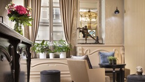 Una habitación con un piano, un sofá, una mesita con plantas y una estatua decorativa.