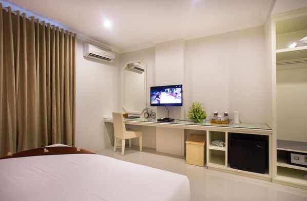A hotel room with a bed, a desk with a computer, a television, and a wardrobe.