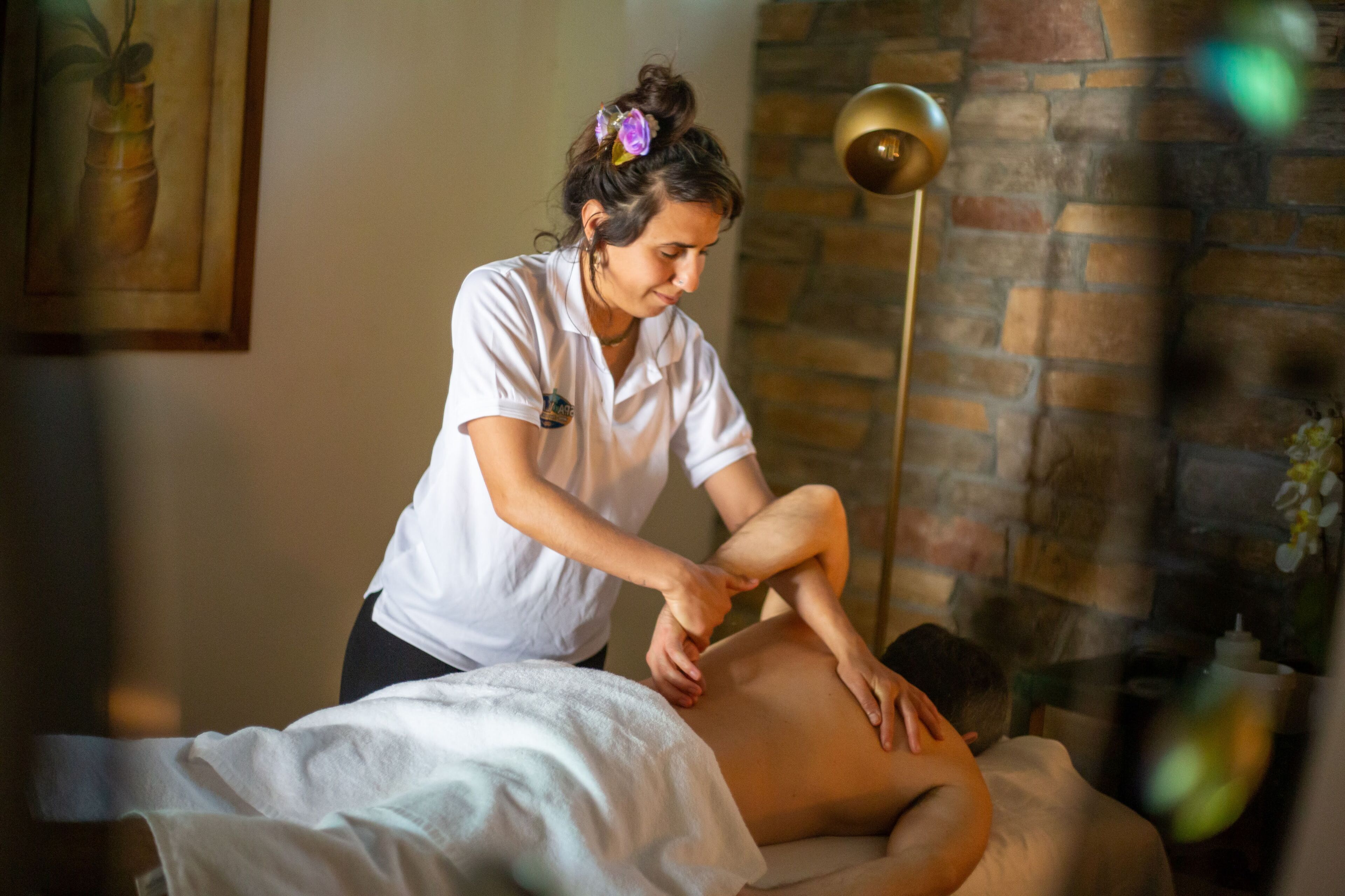 A massage therapy session in a room with a brick wall and a framed artwork.