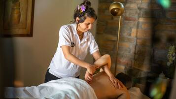 A massage therapy session in a room with a brick wall and a framed artwork.