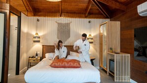 A cozy bedroom with a large bed, wooden ceiling beams, and a hanging light fixture. - Spa Village Adults Only (Hamat Gader)