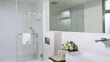 A modern bathroom with a white sink, a glass-enclosed shower, and a toilet.