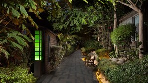 A pathway flanked by lush greenery and a bench, leading to a building with a visible entrance. - Spa Village Adults Only (Hamat Gader)