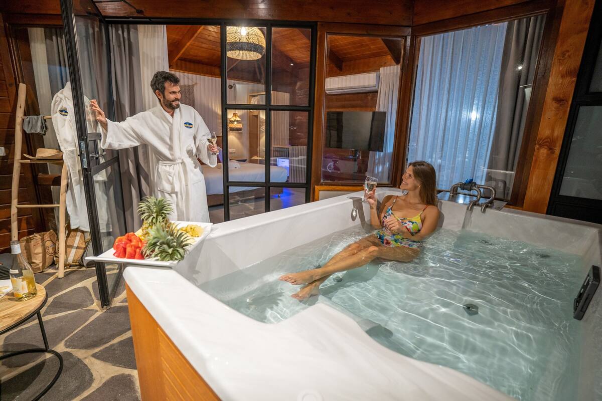 A woman relaxing in a hot tub with a man standing beside her.