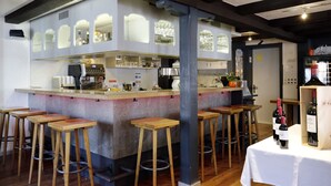 A bar area with wooden stools, a bar counter, and wine bottles. - Hotel Krone (Attinghausen)