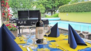 A table set with wine glasses, a bottle, and a grill, overlooking a pool. - Hotel Krone (Attinghausen)