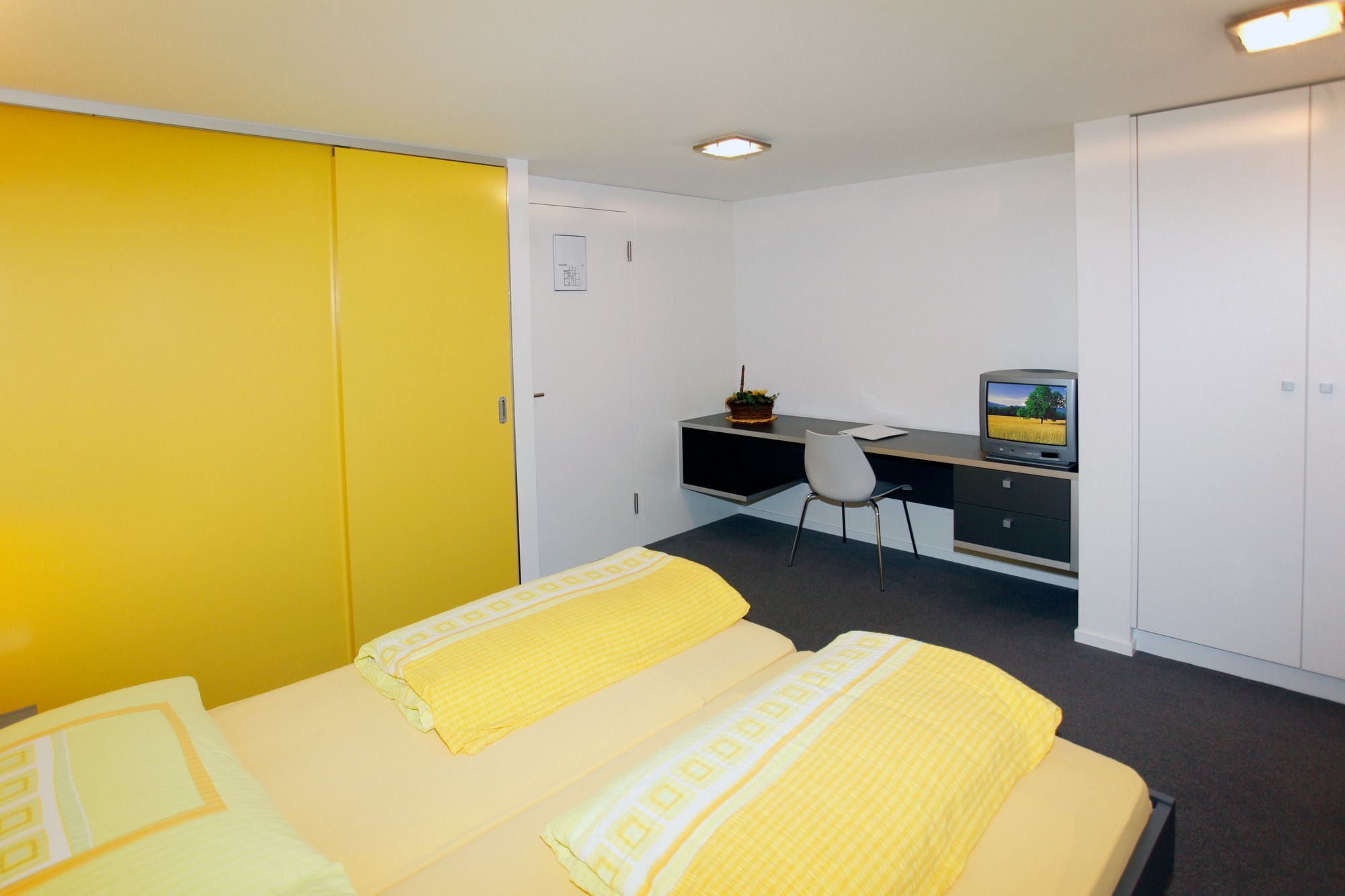 A hotel room with two beds, a desk with a computer, and a television.