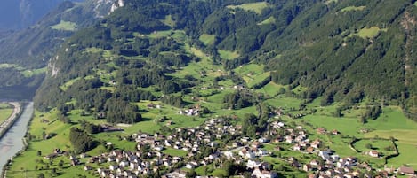 Un pueblo situado en un valle, con un río y rodeado de montañas.
