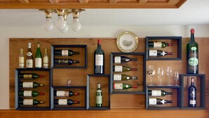 A wine display with multiple bottles and glasses on wooden shelves against a wall. - Hotel Krone (Attinghausen)