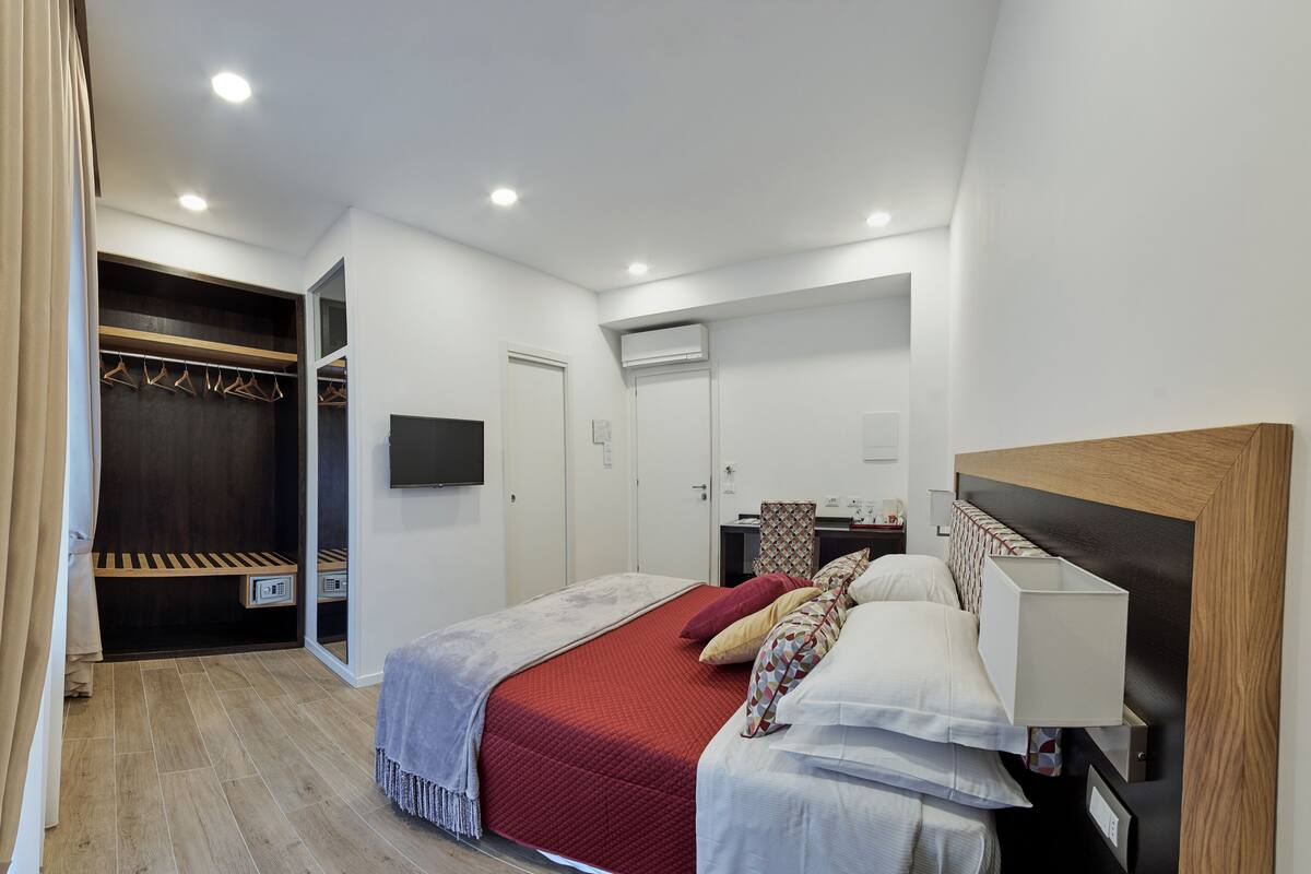 Un dormitorio moderno con cama, mesita de noche y armario con espejo.