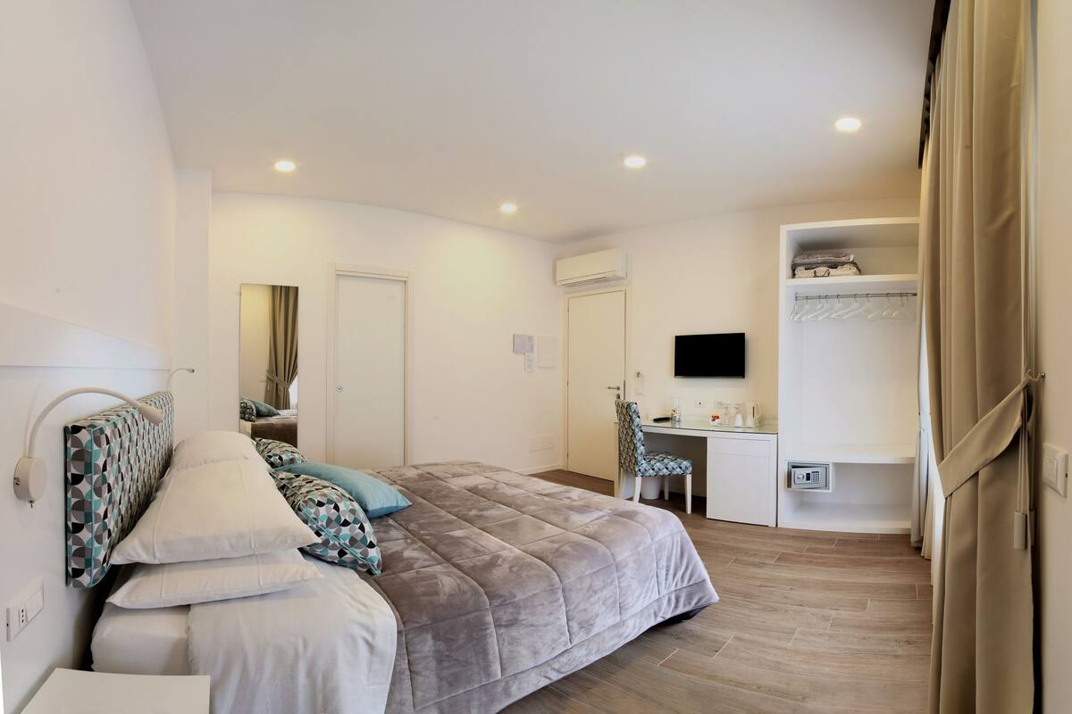 Un dormitorio moderno con cama, mesita de noche y escritorio con silla.