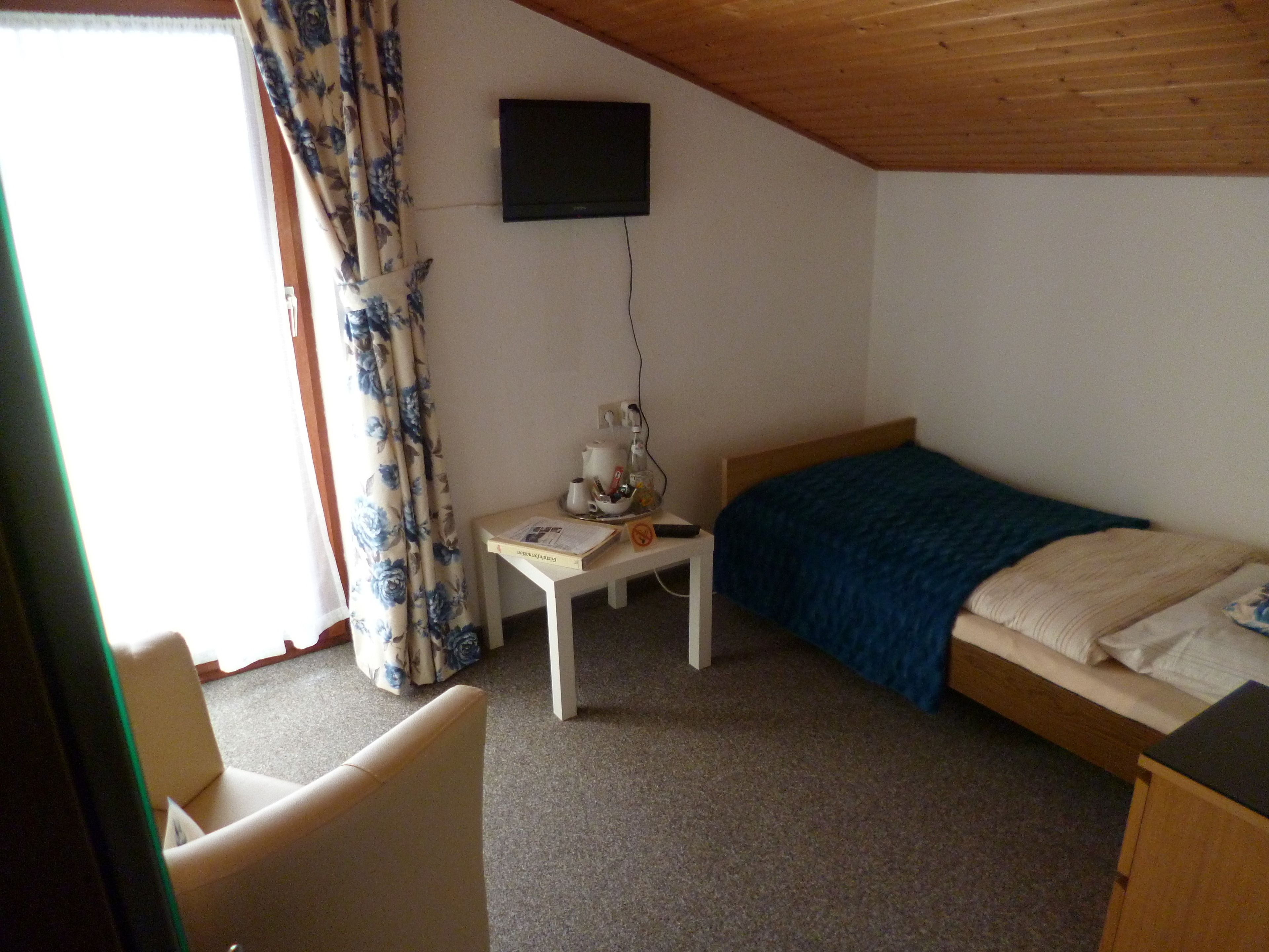 Een kleine, netjes ingerichte kamer met een enkel bed, een bureau en een stoel.